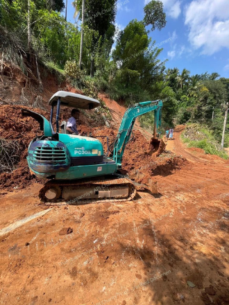 Excavator clearing a roadway in a steep slope area