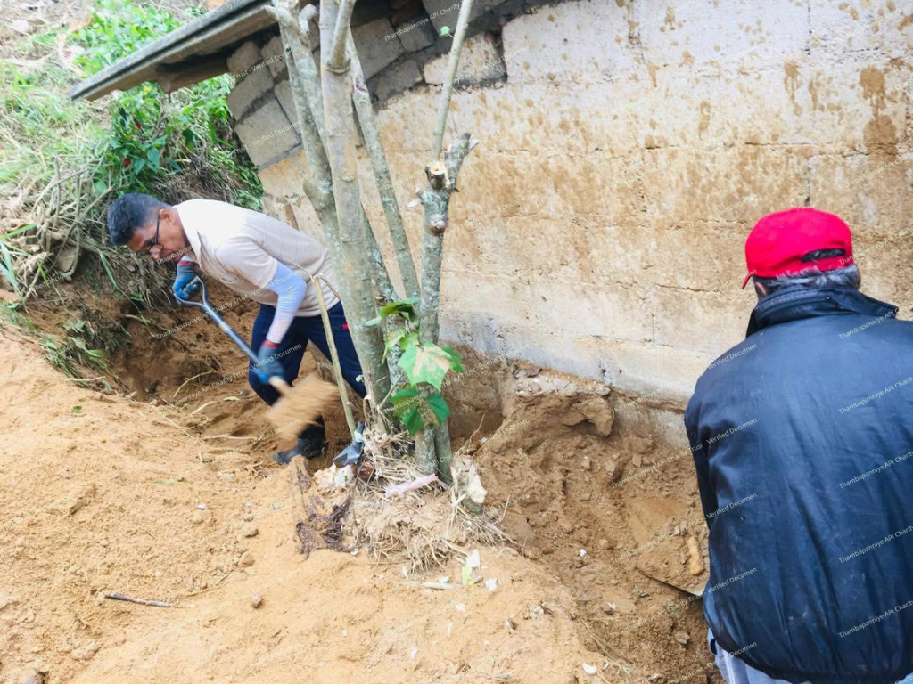 Wall collapse next to a house with residents removing soil